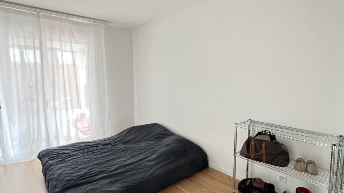 Schlafzimmer mit großem Fenster und einfachem Bett